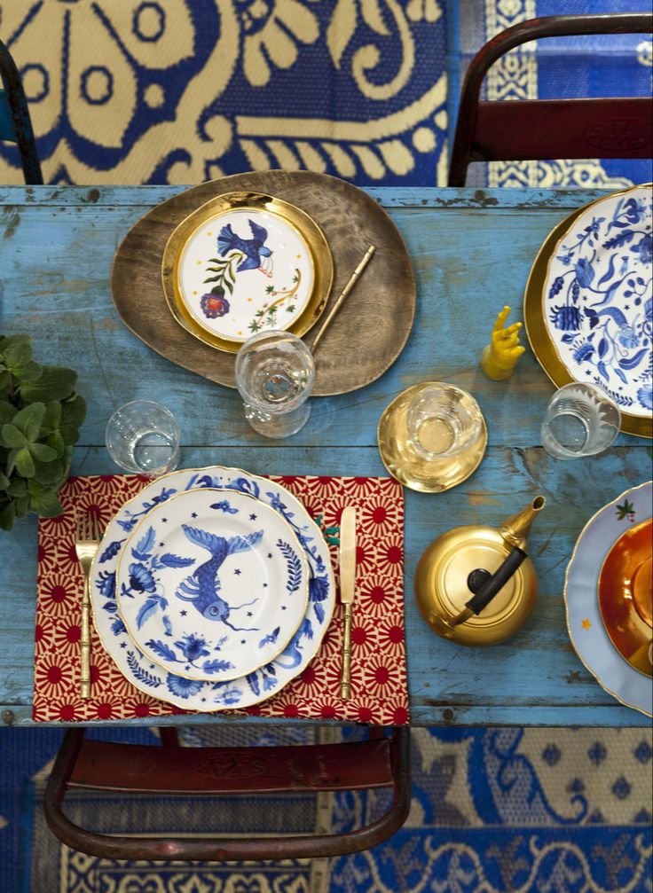 the table is set with blue and white plates, silverware, and other items