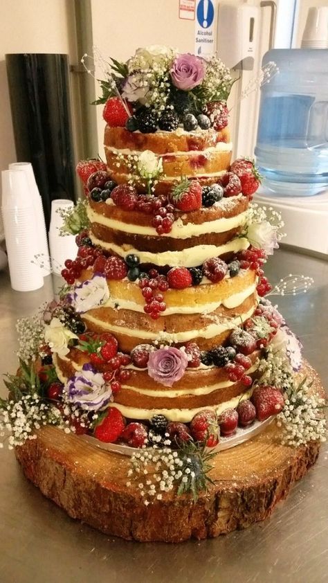 a multi layer cake with flowers and berries on top