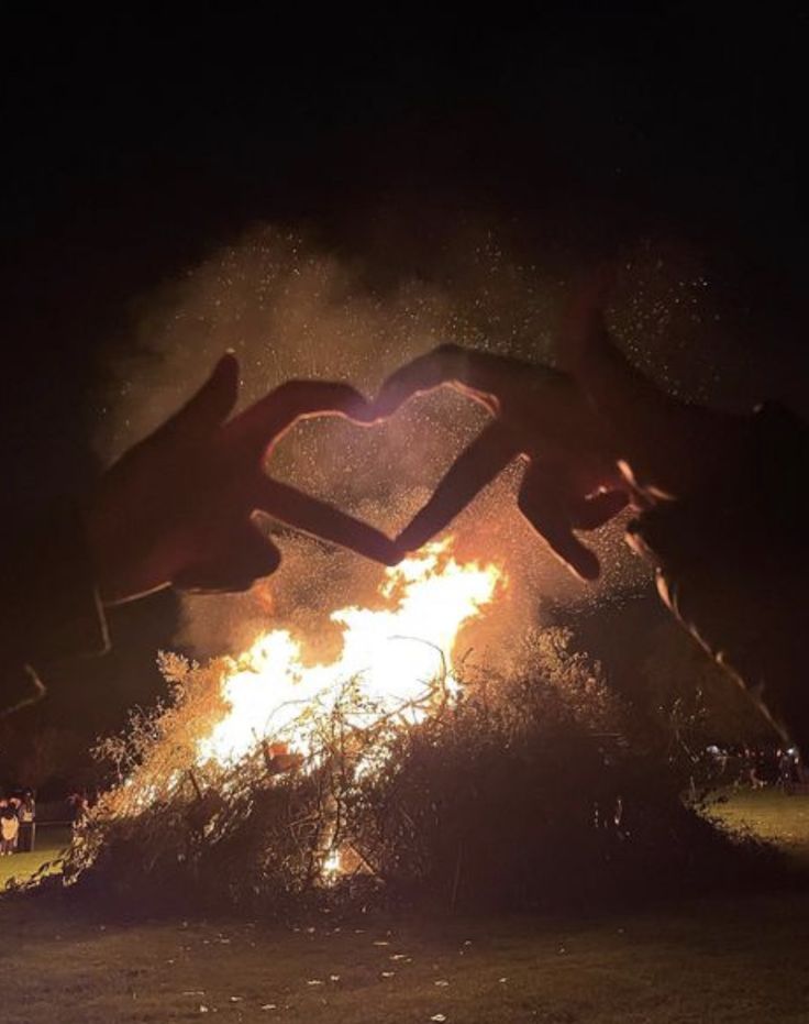 two people jumping over a fire with their hands in the air