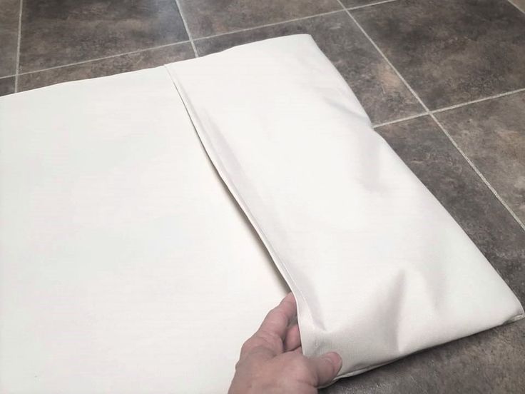 someone is making a pillow case out of white sheets on the floor with their hands