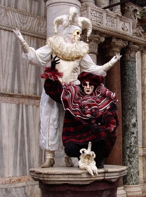 two creepy clowns standing next to each other in front of an old building with columns