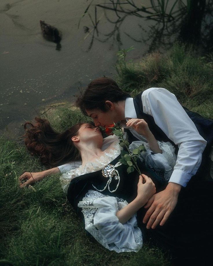 a woman laying on the ground next to a man in a white shirt and black dress