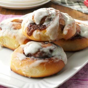 three cinnamon rolls with icing on a white plate