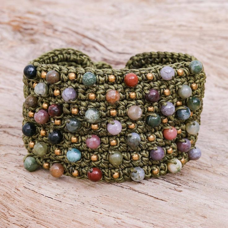 a close up of a bracelet on a wooden surface with beads and stones in it