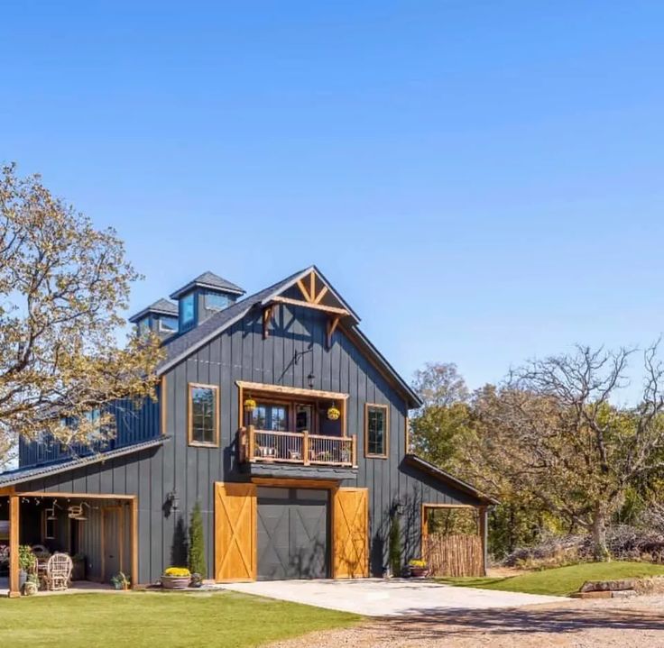 a large gray barn with two story windows on the front and second story above it