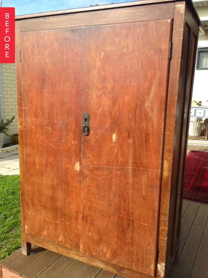 an old wooden cabinet sitting on top of a wooden deck next to a red rug