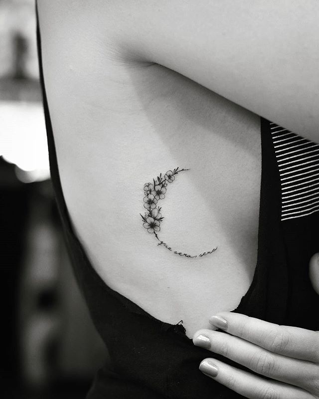 a woman's upper arm with a small flower tattoo on the left side of her shoulder