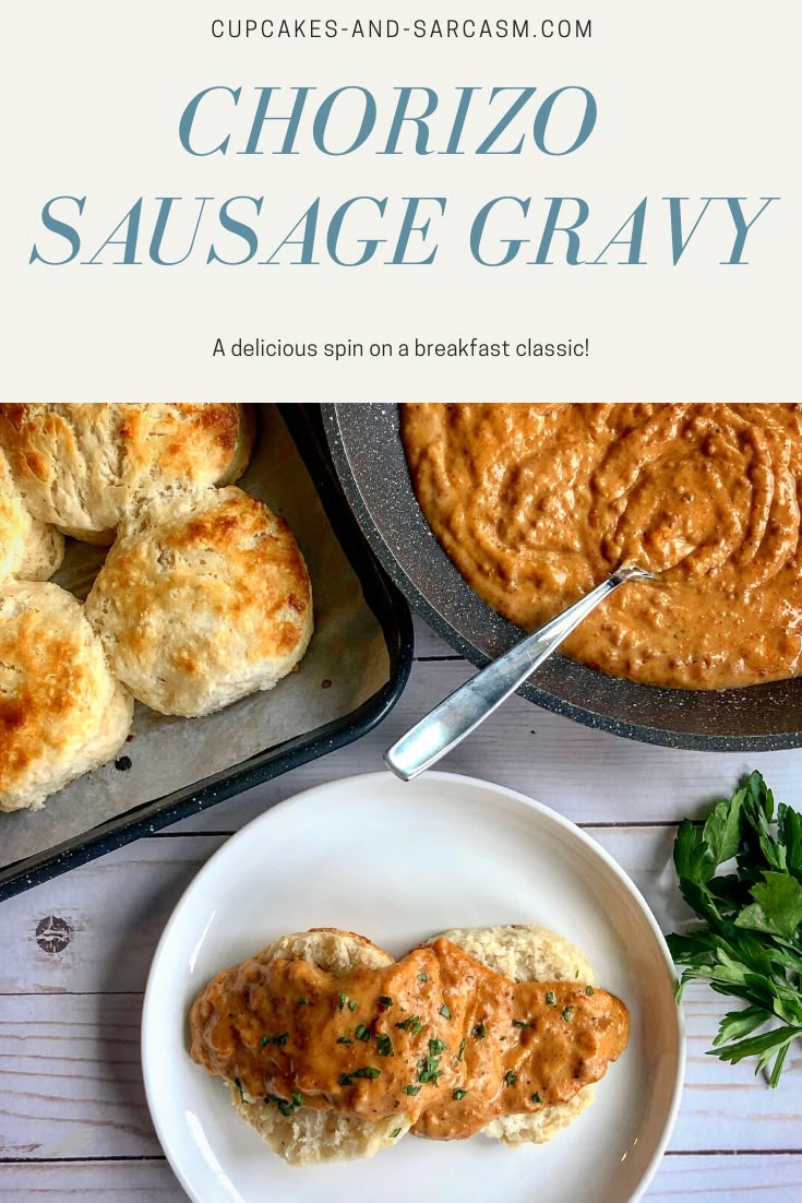 a white plate topped with cheesy sausage gravy next to some biscuits