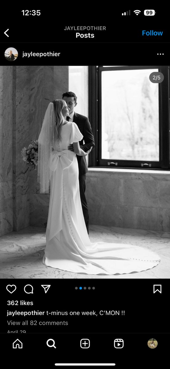 black and white photo of bride and groom kissing in front of window at their wedding