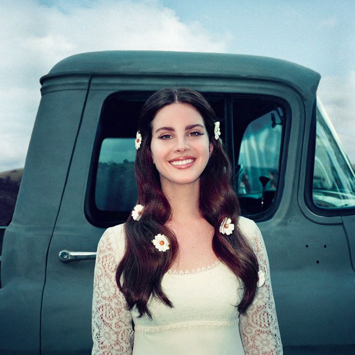 the woman is posing in front of a truck wearing a white dress and holding her hand up to her ear