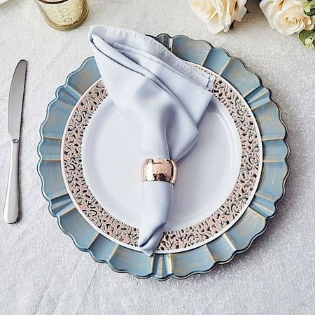 a place setting with napkins and silverware on a white tableclothed table