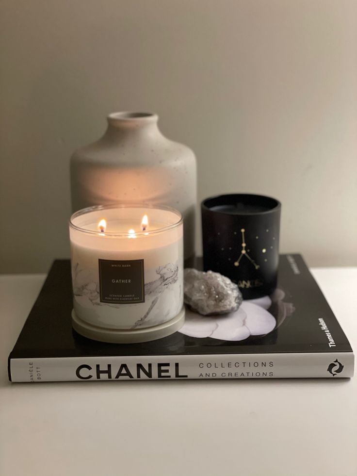 two candles sitting on top of a book next to a vase and other items in front of it