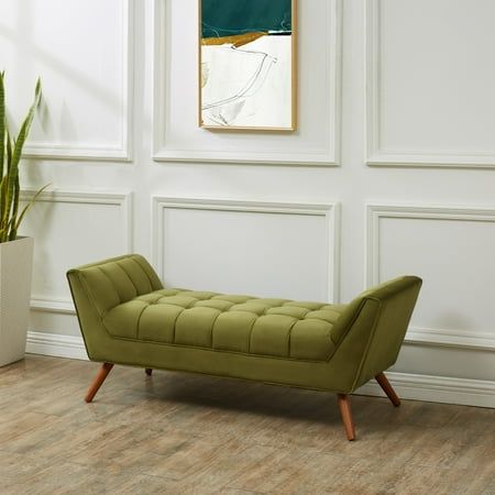 a green bench sitting in front of a white wall with a painting on the wall