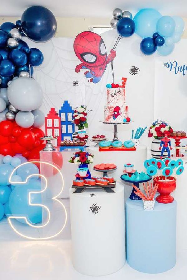 a birthday party with spiderman decorations, balloons and streamers on the wall behind it