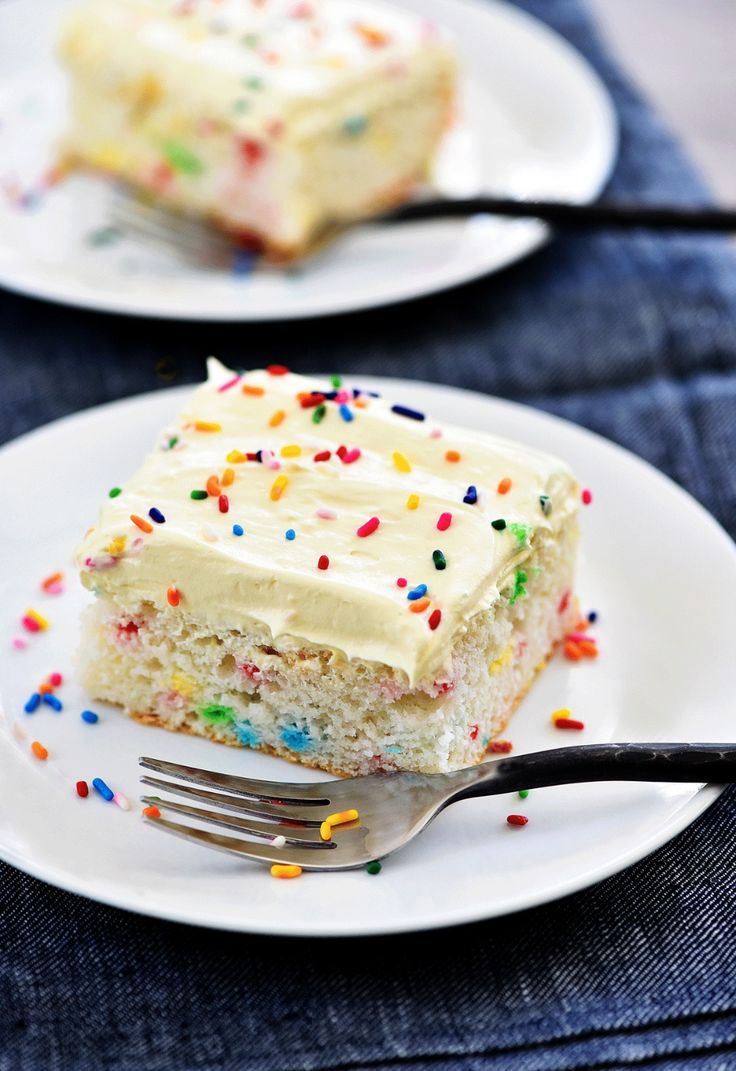 a piece of cake with white frosting and sprinkles on two plates