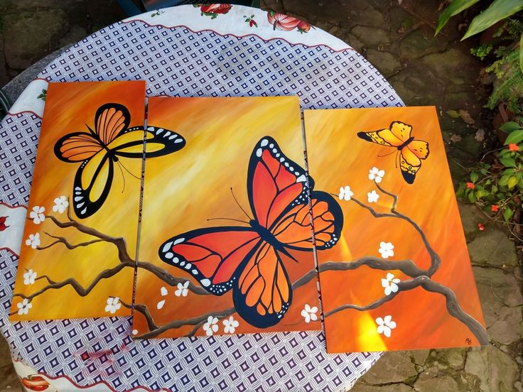 two butterflies painted on canvases sitting on a table