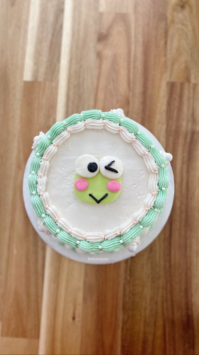 a close up of a cake on a wooden table with a face painted on it