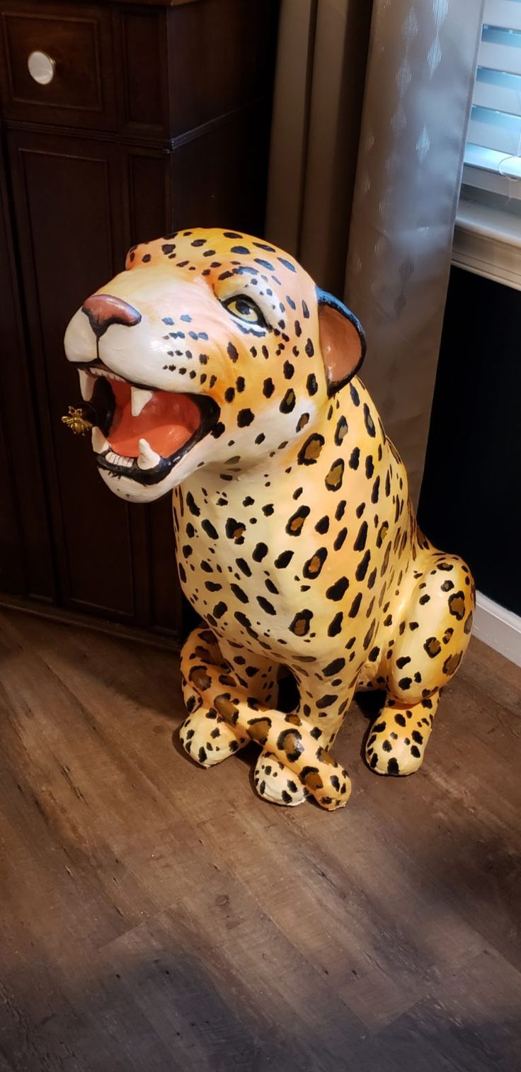 a large statue of a cheetah sitting on the floor next to a window