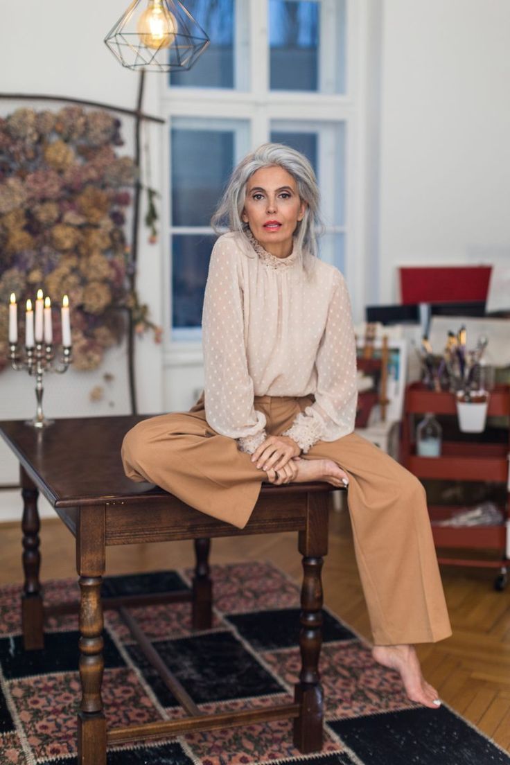 a woman sitting on top of a wooden table in front of a chandelier