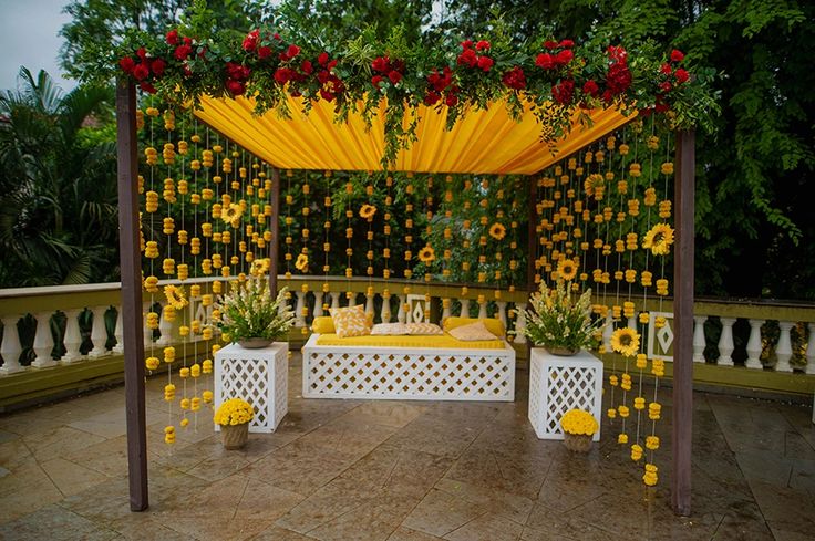 an outdoor wedding setup with yellow and red flowers on the arbor, surrounded by greenery