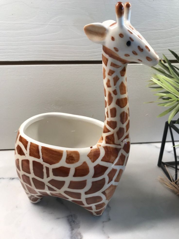 a ceramic giraffe planter sitting next to a potted plant