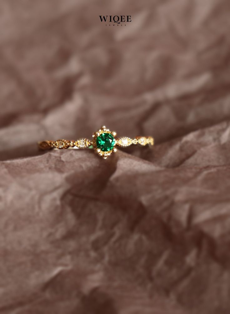 a gold ring with a green stone in the middle