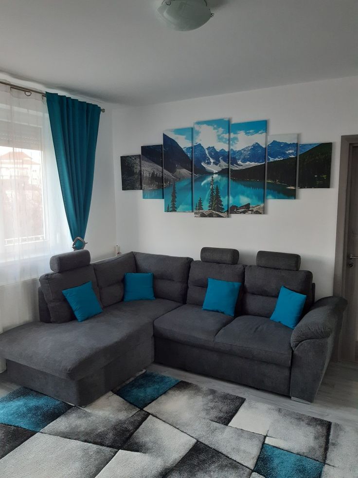 a living room with grey couches and blue throw pillows on the rug in front of it