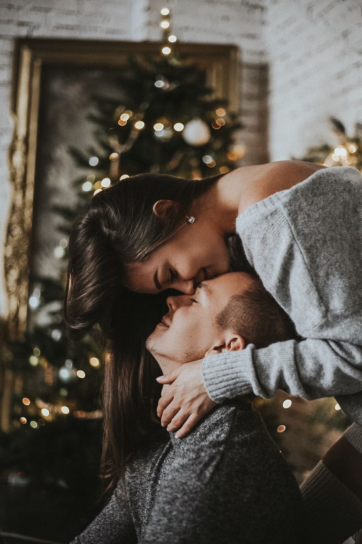 a man and woman kissing in front of a christmas tree