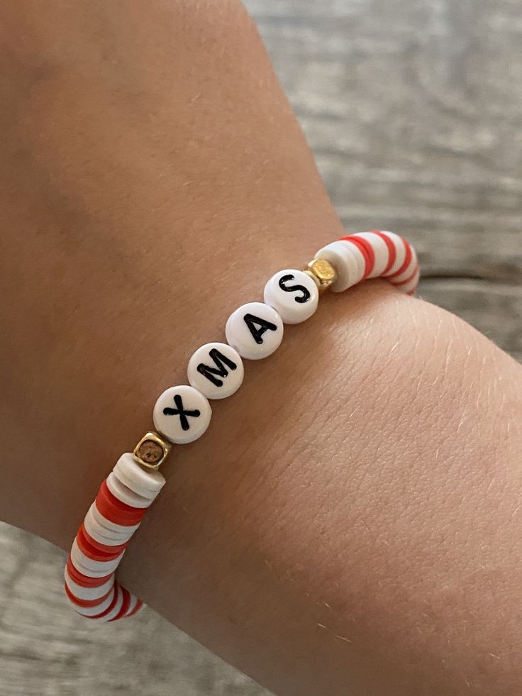 a woman's arm wearing a red and white bracelet with the word sas on it