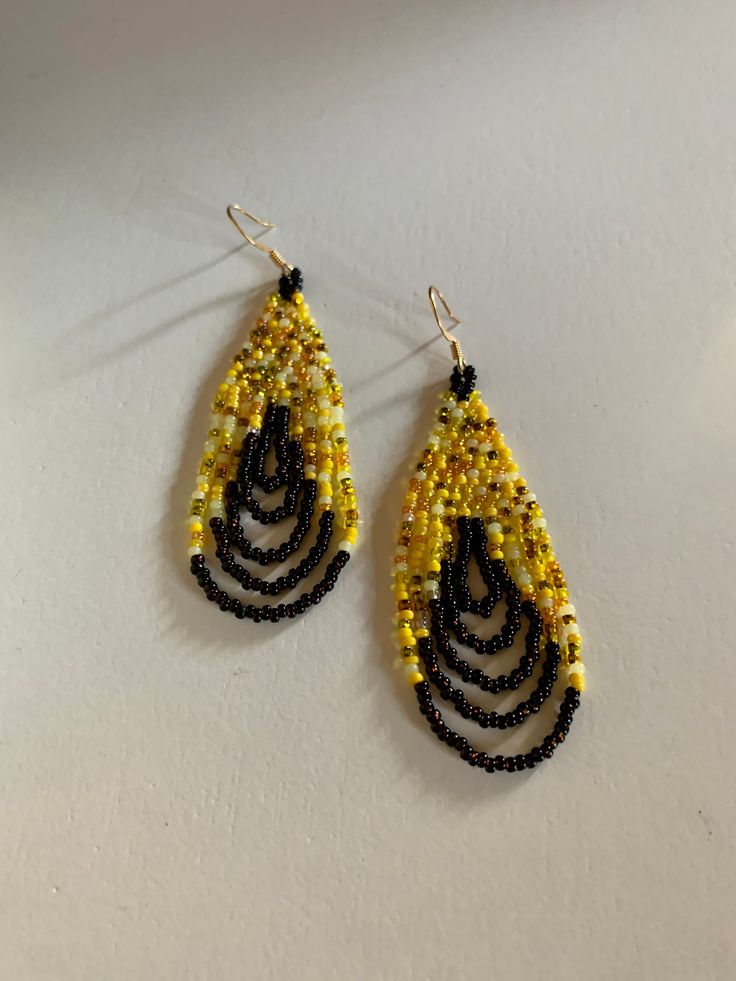 These are a great bright set of earrings that have a fun yellow bead mix that are well balanced out by the dark brown swag at the bottom. Yellow Beaded Teardrop Earrings, Yellow Teardrop Beaded Earrings With Colorful Beads, Yellow Teardrop Beaded Earrings With Dangling Beads, Yellow Beaded Earrings With Black Beads, Yellow Dangle Hoop Earrings With Ear Wire, Yellow Teardrop Earrings With Dangling Beads, Yellow Gold Beads Drop Earrings, Yellow Gold Beaded Drop Earrings, Adjustable Yellow Earrings With Gold Beads