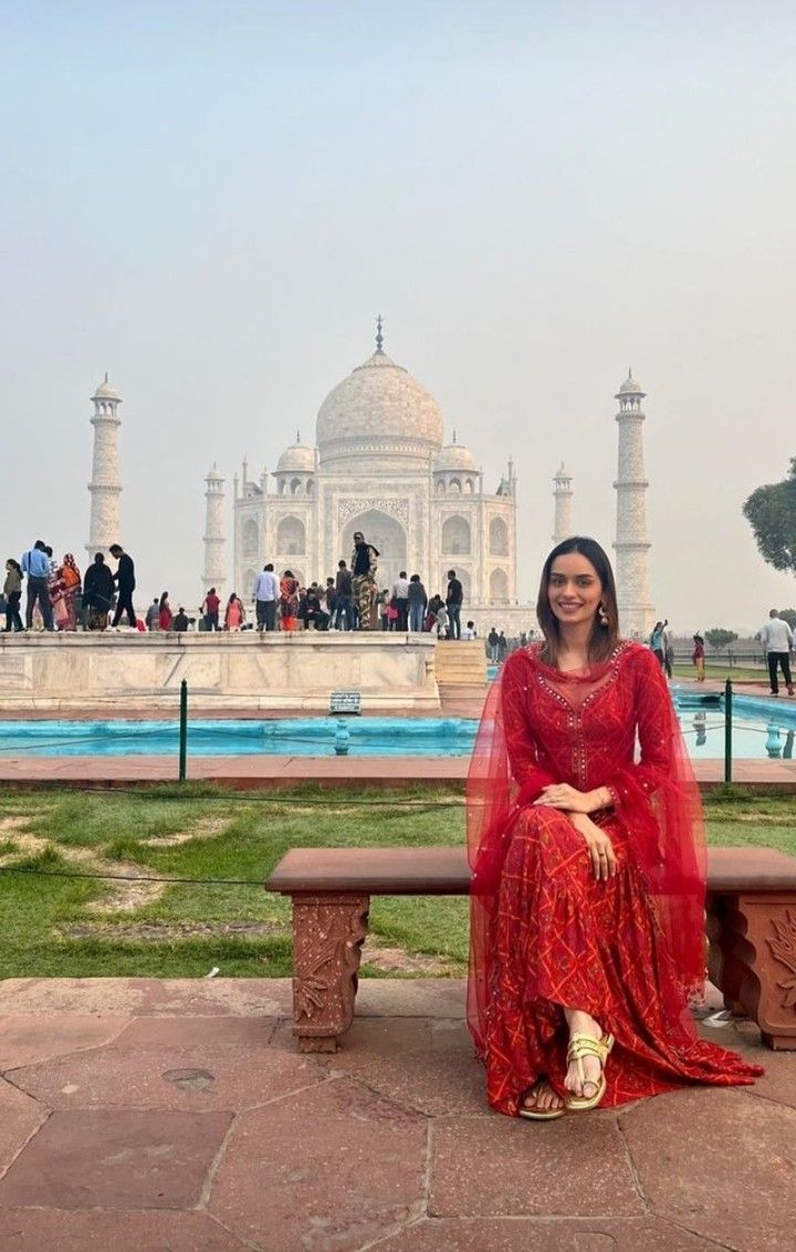 a woman sitting on a bench in front of the taj - izzar