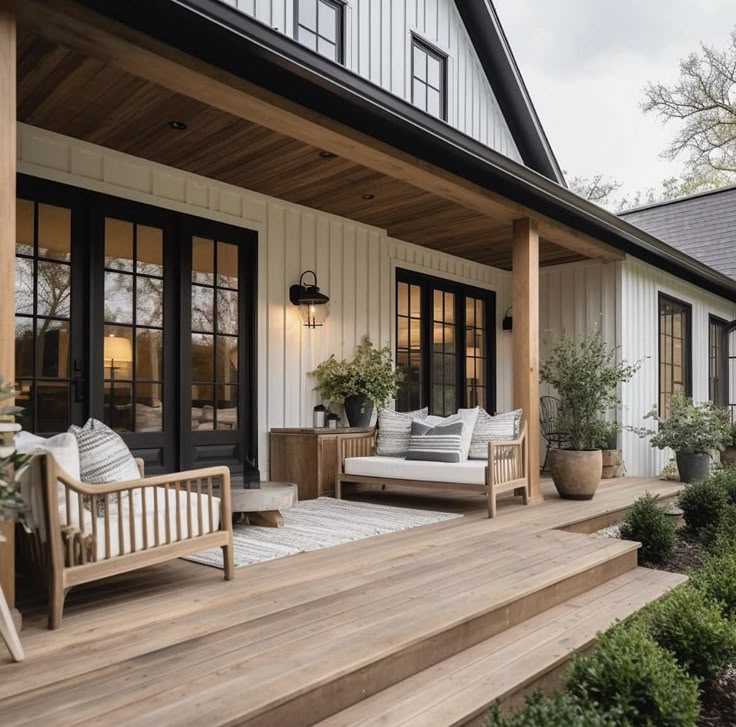 a porch with two couches and potted plants on the steps leading up to it