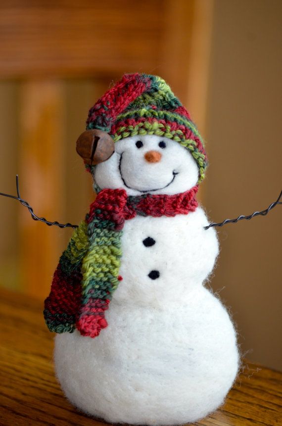 a white snowman with a green and red scarf on it's head is sitting on a table