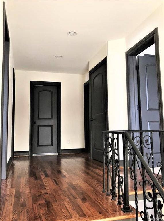 an empty room with wooden floors and black doors on either side of the door is a set of stairs