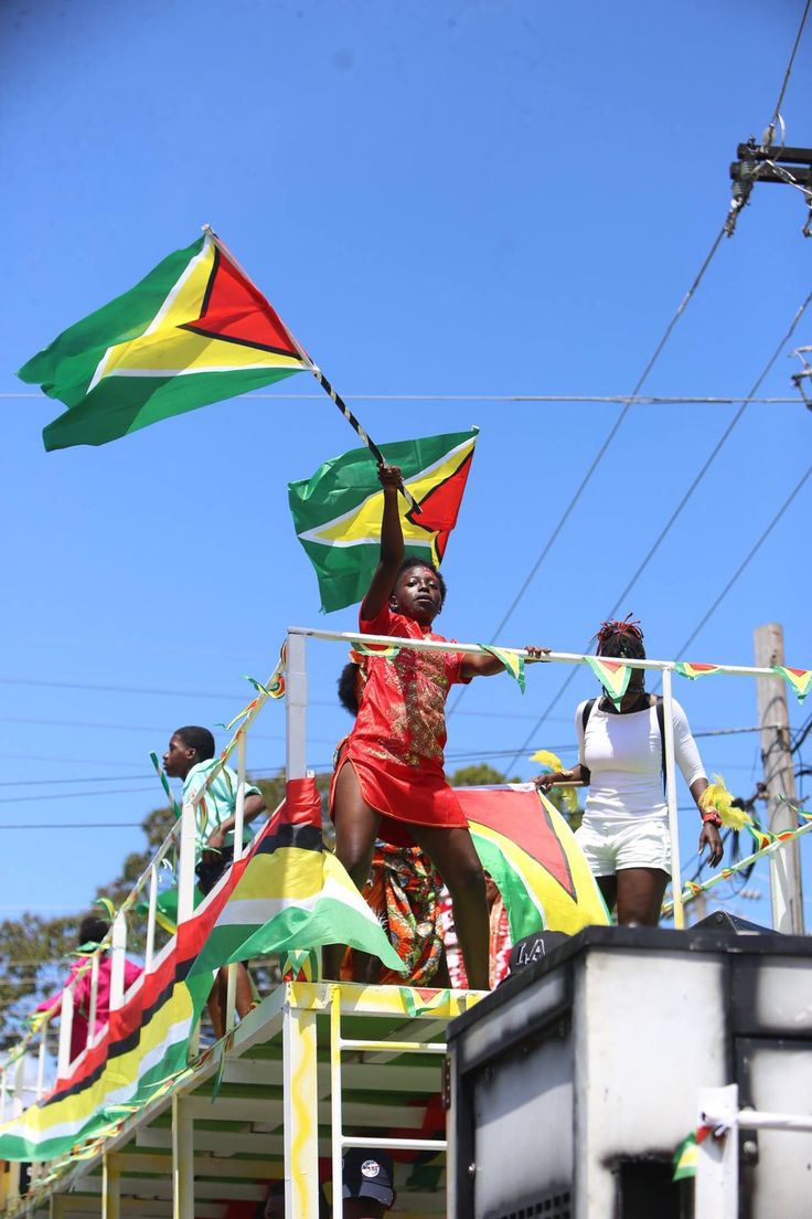 a group of people riding on the back of a truck with flags flying in the air