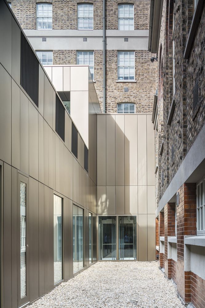 an empty courtyard between two buildings with glass doors on each side and brick walls in the background