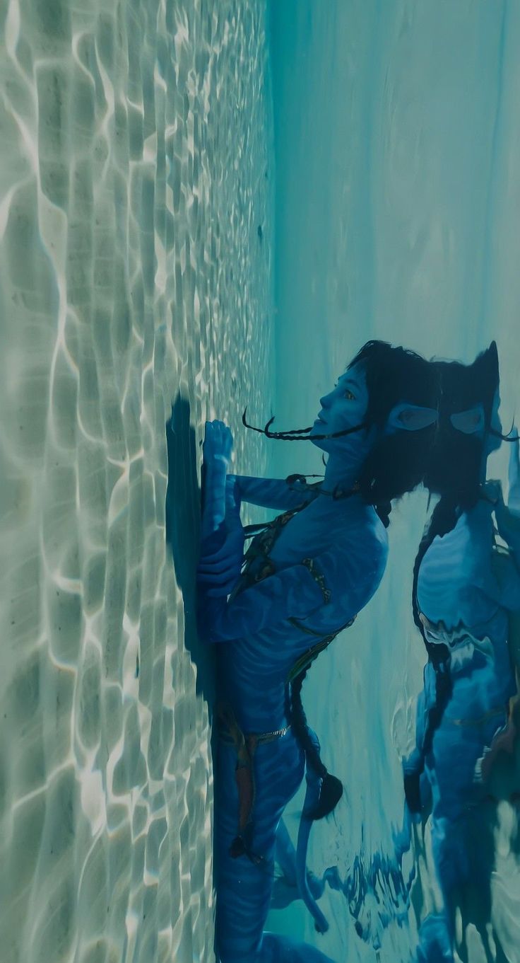 the reflection of a person standing in water next to a wall with blue paint on it