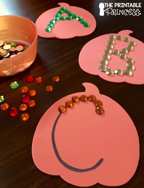 some pink paper pumpkins are sitting on a table with beads and other items around them