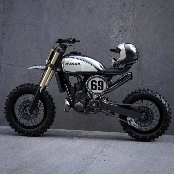 a white and black dirt bike parked in front of a gray wall with the number 69 on it