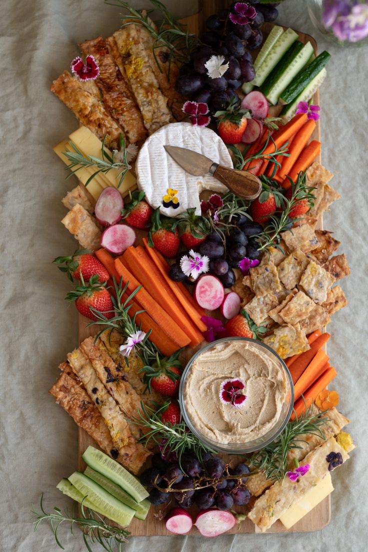 a platter with carrots, celery, strawberries, grapes and crackers