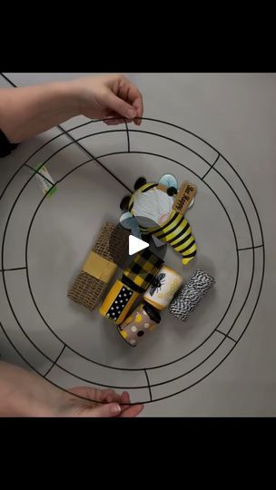 two hands are holding small objects on a circular object that looks like a bee and beeshive