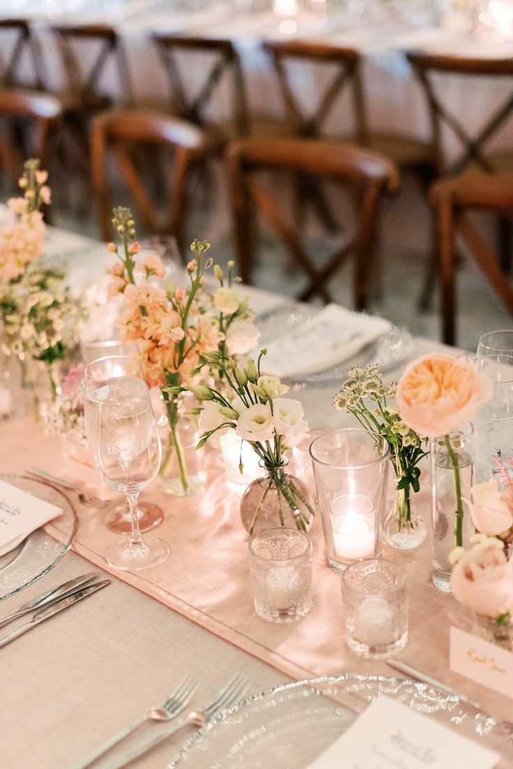 the table is set with flowers and place settings for guests to sit down at it