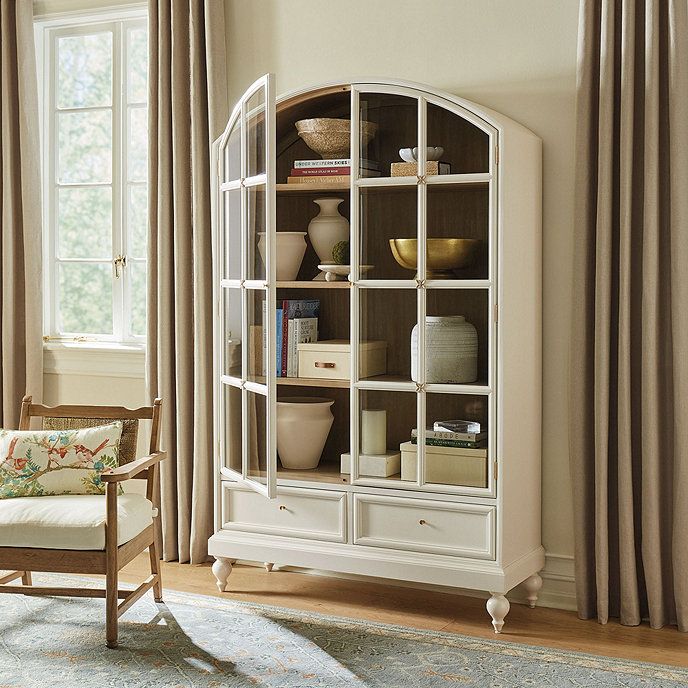 a living room with a chair, bookcase and window