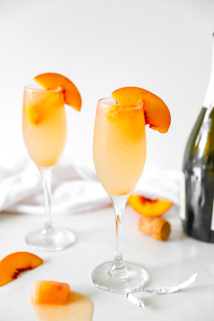 two glasses filled with drinks next to a bottle and some orange peels on the table