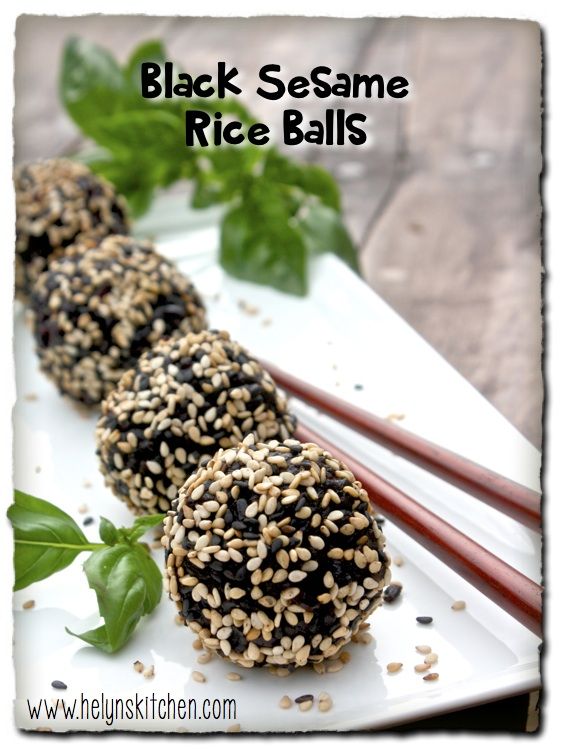 black sesame rice balls on a white plate with chopsticks and greens in the background