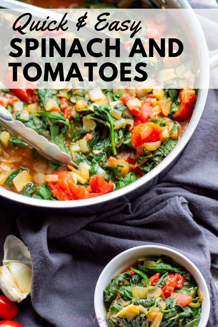 spinach and tomato soup in a white bowl with a spoon on the side next to tomatoes