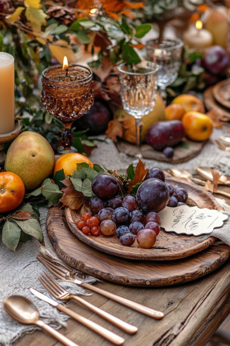 the table is set with fruit, candles and silverware for an elegant fall dinner