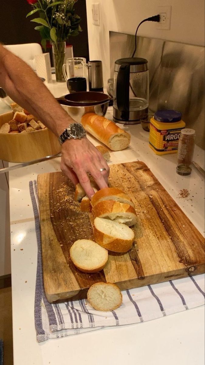 a person is cutting bread on a wooden board