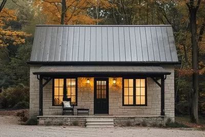 a small house with a metal roof in the woods