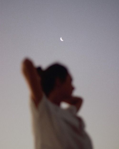 a person is flying a kite with the moon in the sky behind them and an object that looks like a half moon